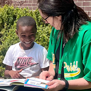 Adult and child sitting outside with a book