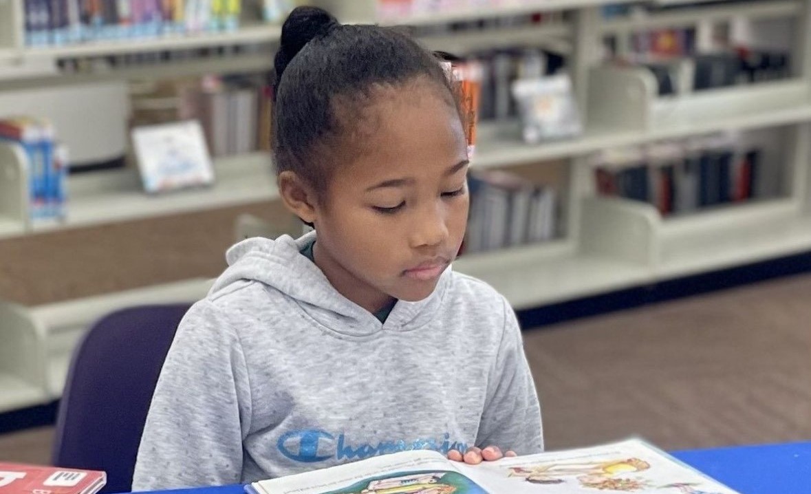 Young girl reading a book in the library